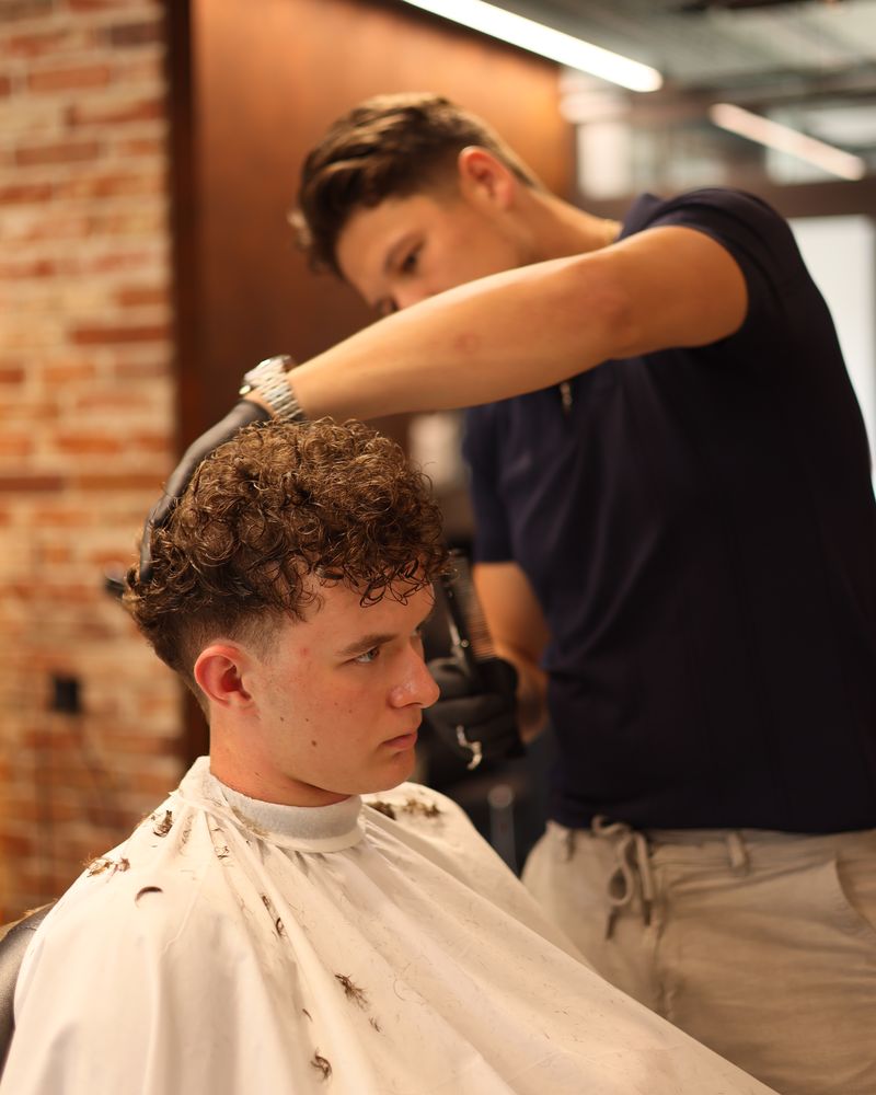 Marcin, barber Złotobrody, strzyże kręcone włosy klienta w salonie